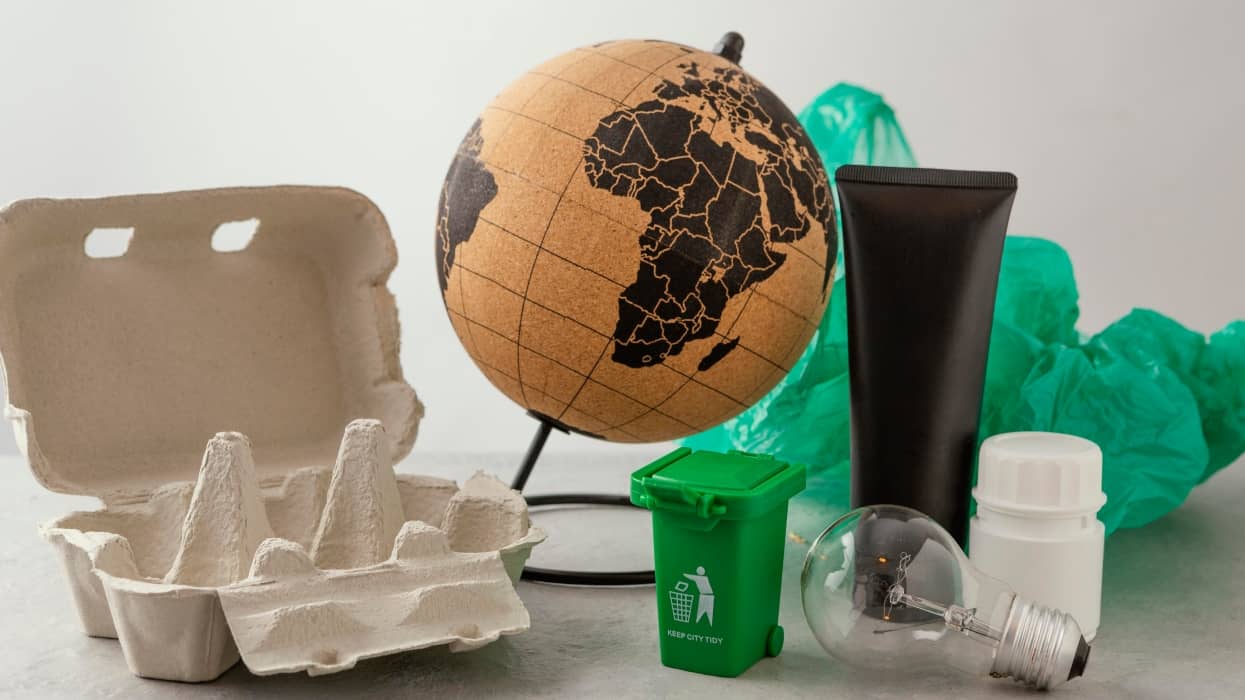 Conjunto de objetos: una bola del mundo, bolsas de plástico, huevera de cartón, bombilla de cristal y bote de crema