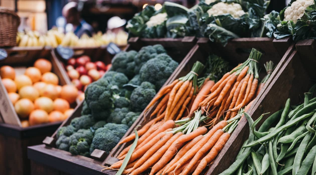 Habichuelas, zanahorias y brócolis en una caja de madera en el mercado