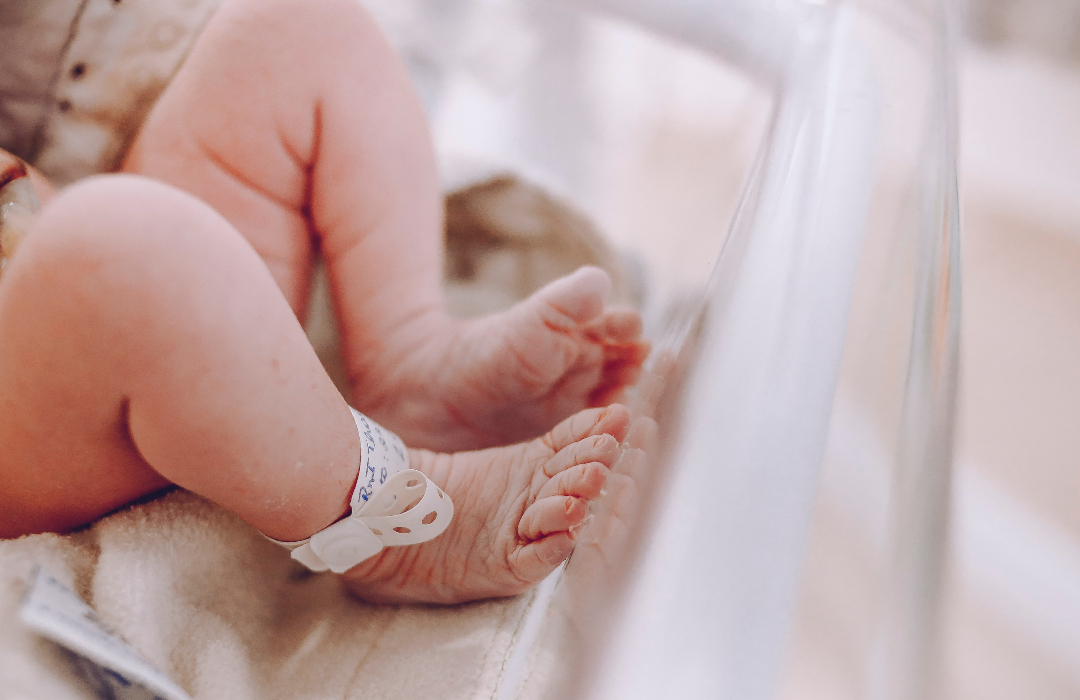 piernas de un bebé con pulsera identificativa dentro de una incubadora