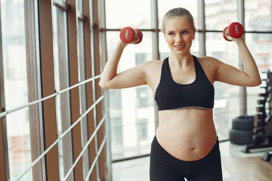 Mujer embarazada haciendo pesas en un gimnasio