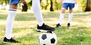 Primer plano de unas piernas de niños jugando al fútbol en un césped