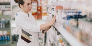 Una joven Técnico de Farmacia comprobando los productos en las estanterías de una farmacia