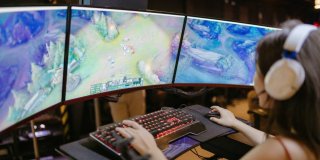 Chica jugando a League of Legends con tres monitores y teclado iluminado