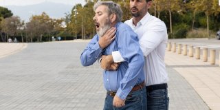 hombre realizando la maniobra heimlich a otro hombre que se está atragantando