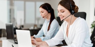 dos personas trabajando con ordenadores y realizando llamadas