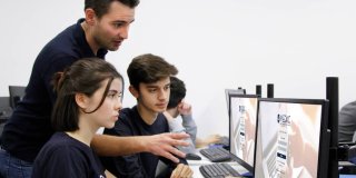 Un profesor explicando a dos alumnos algún tema en el ordenador