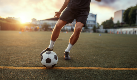 Primer plano de unas piernas de futbolista yendo detrás de un balón