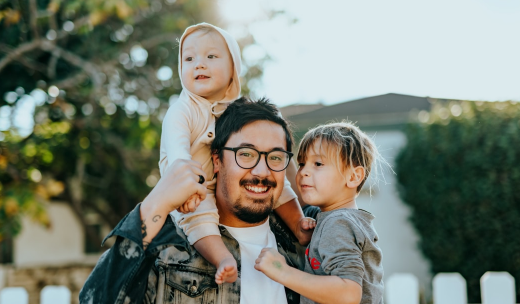 Padre con sus hijos pequeños en brazos y sobre los hombros