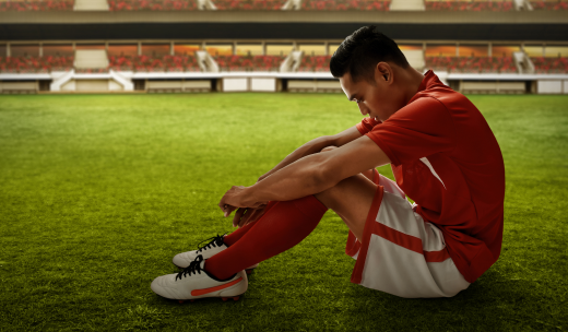 Futbolista pensativo sentado en el césped de un campo de fútbol