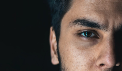 Primer plano de un hombre con pelo oscuro y abundante sobre fondo negro