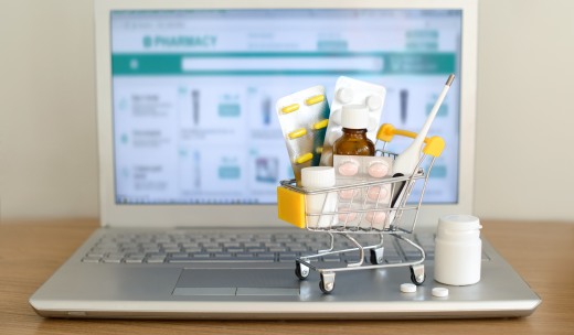 Un mini carrito con productos farmacéuticos encima de un portátil