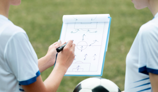 Entrenador explicándole a un futbolista la estrategia de juego en un dibujo