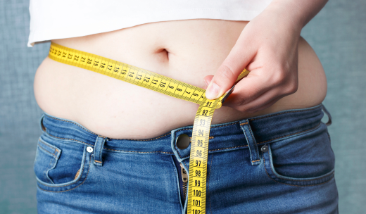 Barriga de una persona obesa rodeada por una cinta métrica