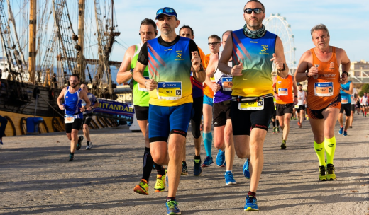 Deportistas participando en un maratón junto al muelle de la ciudad