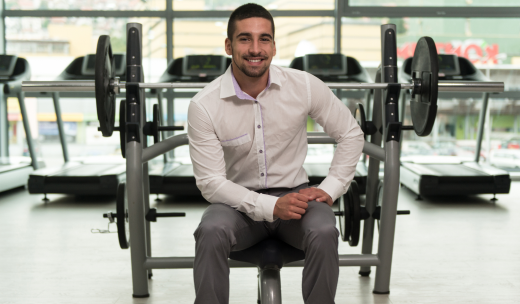 Hombre sonriente en traje sentado en unas máquinas de gimnasio