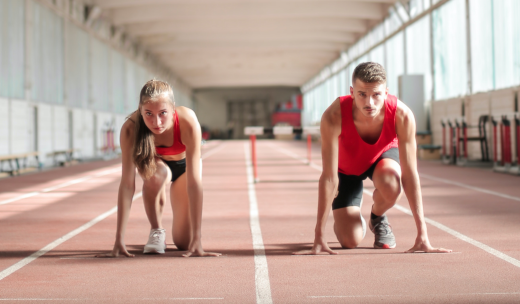 Una mujer y un hombre en posición de correr en una pista de atletismo