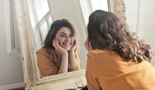 Mujer mirándose al espejo sonriéndose a sí misma