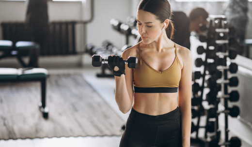 Primer plano de una mujer realizando ejercicio de pesas en una sala de gimnasio