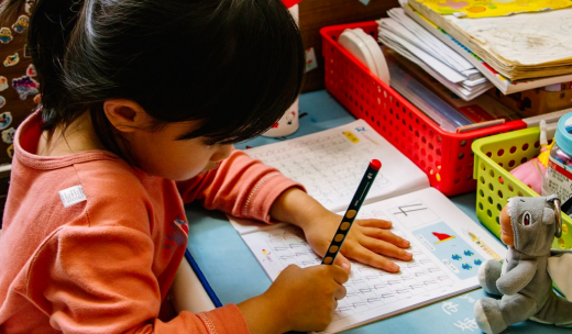 Primer plano de una niña pequeña escribiendo en su cuaderno de clase