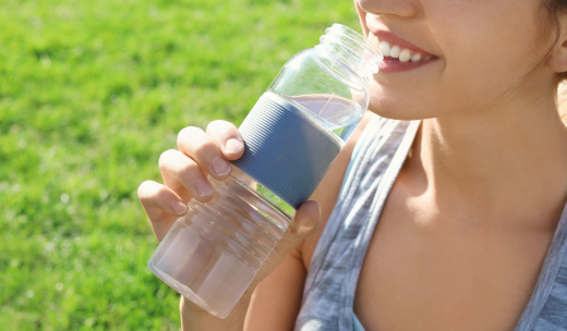 Primer plano de una mujer cogiendo una botella de agua y llevándosela a la boca