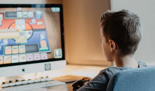 Niño pequeño sentado frente al ordenador con un juego didáctico