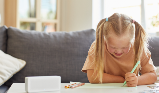 Niña rubia pintando con diferentes lápices encima de una mesa