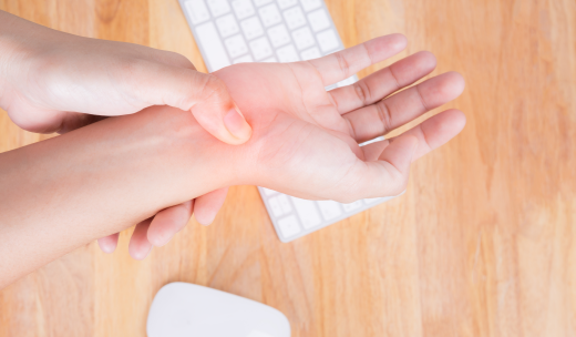 Persona sujetándose la muñeca en señal de dolor encima de un teclado