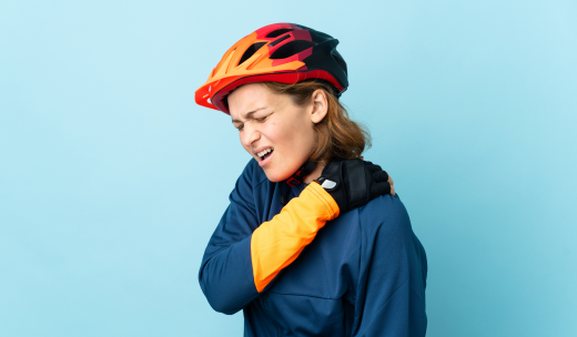 Mujer ciclista con la mano apoyada en su hombro por un dolor