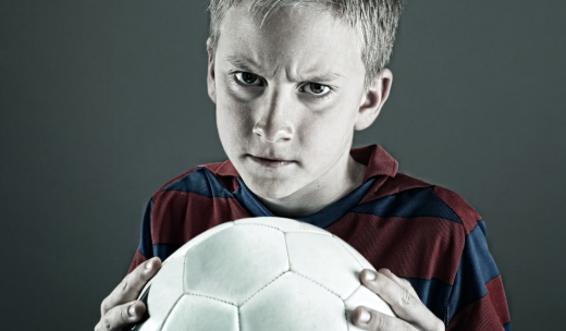 Cara de un niño enfadado con un balón de fútbol entre sus  manos