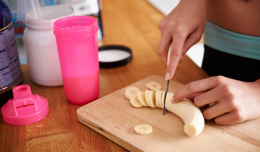 Deportista cortando un plátano para un batido de proteínas