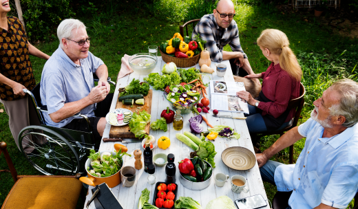 Ancianos entorno a una mesa llena de verduras en un jardín