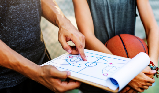 Primer plano de entrenador de baloncesto señalando la jugada en un tablero