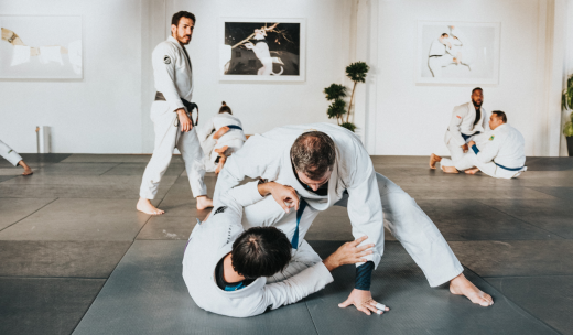 Diferentes personas cursando una clase de judo en una sala