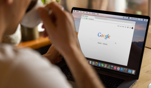 Persona tomando un café mientras hace una búsqueda en Google con su portátil