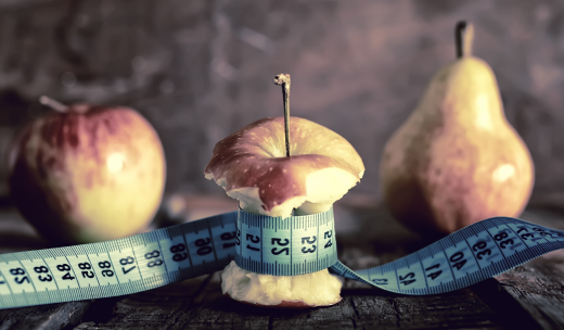 Primer plano de una cinta métrica rodeando a una manzana mordida