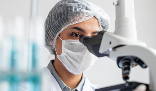 Primer plano de una investigadora mirando a través de un microscopio