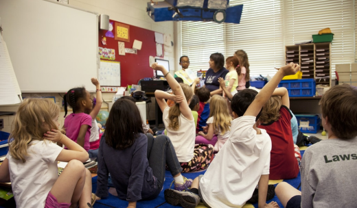 Grupo de niños y niñas sentados en clases escuchando a su profesora