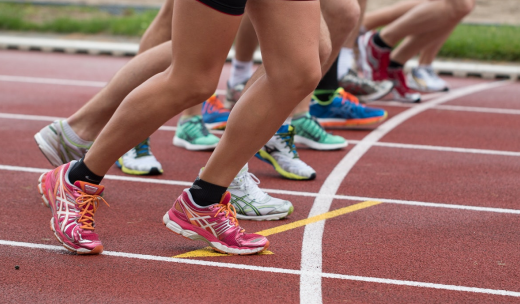 Piernas de atletas preparándose para correr en una pista de atletismo