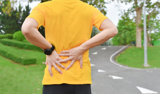 Corredor de espaldas sujetándose la zona lumbar en señal de dolor