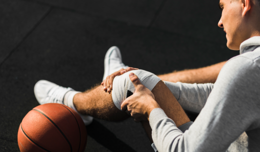 Jugador de baloncesto en el suelo tocándose la pierna tras sufrir una lesión