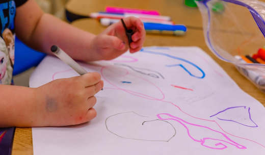 Unas manos de un niños pequeño dibujando con un rotulador
