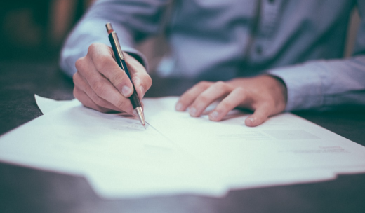 Dos manos y una de ella cogiendo un bolígrafo para firmar papeles
