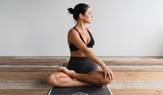 Una mujer en una esterilla haciendo una postura de yoga
