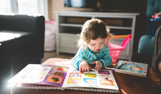 Una niña pequeña viendo unos cuentos infantiles encima de una mesa
