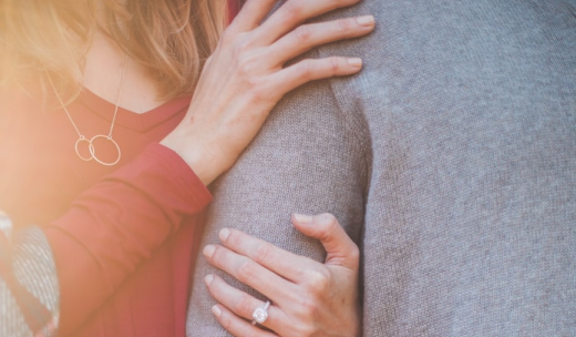 Manos de una mujer con un anillo agarrando el brazo de un hombre