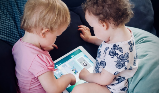 Dos bebés de espalda con una tablet