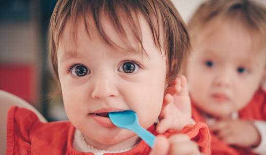 Un bebé con una cuchara de plástico en la boca