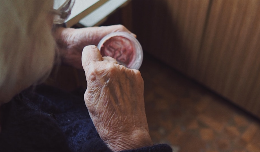 Manos de una anciana comiendo un yogurt