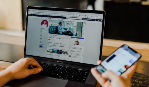 Una persona mirando sus redes sociales en un ordenador portátil y móvil