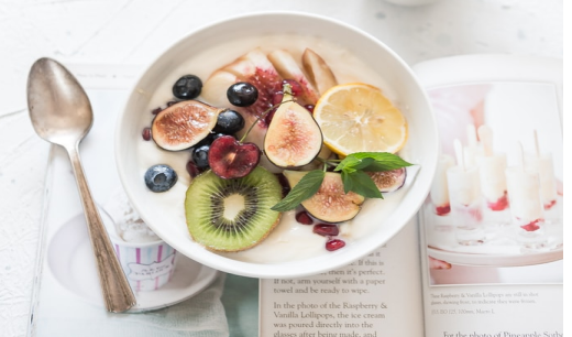 Cuenco con fruta y una cuchara sobre un libro de recetas